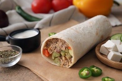 Photo of Delicious tortilla wrap with tuna and vegetables on table, closeup