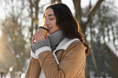 Photo of Portrait of beautiful woman drinking coffee in snowy park
