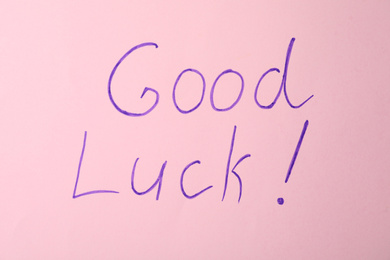 Photo of Phrase GOOD LUCK on pink background, top view