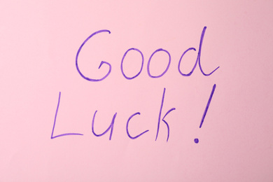 Phrase GOOD LUCK on pink background, top view