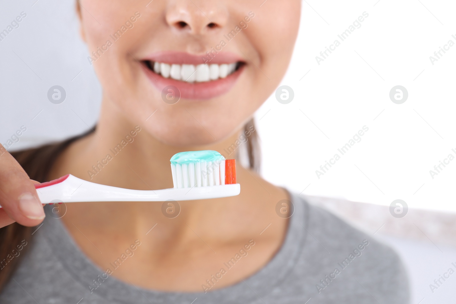 Photo of Young woman with toothbrush and paste on light background, closeup. Teeth care