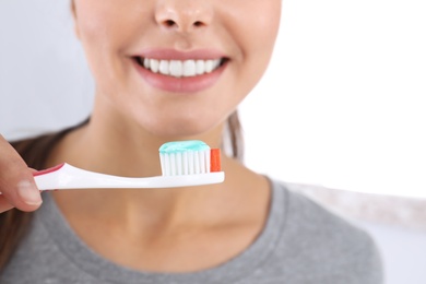 Photo of Young woman with toothbrush and paste on light background, closeup. Teeth care