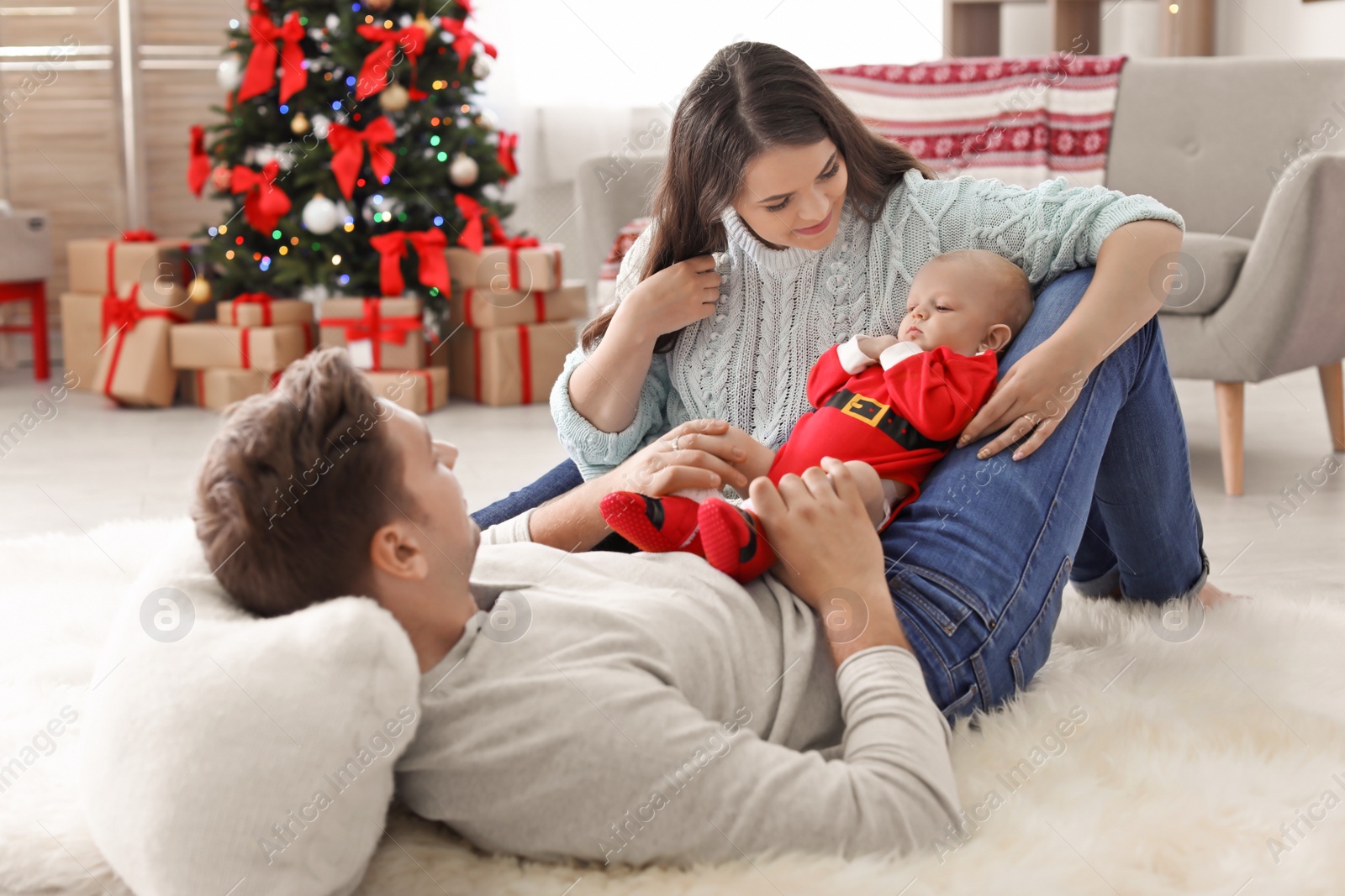 Photo of Happy couple with baby celebrating Christmas together at home