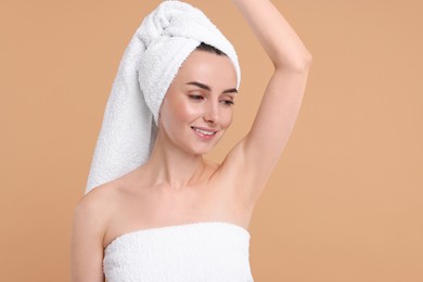 Beautiful woman showing armpit with smooth clean skin on beige background