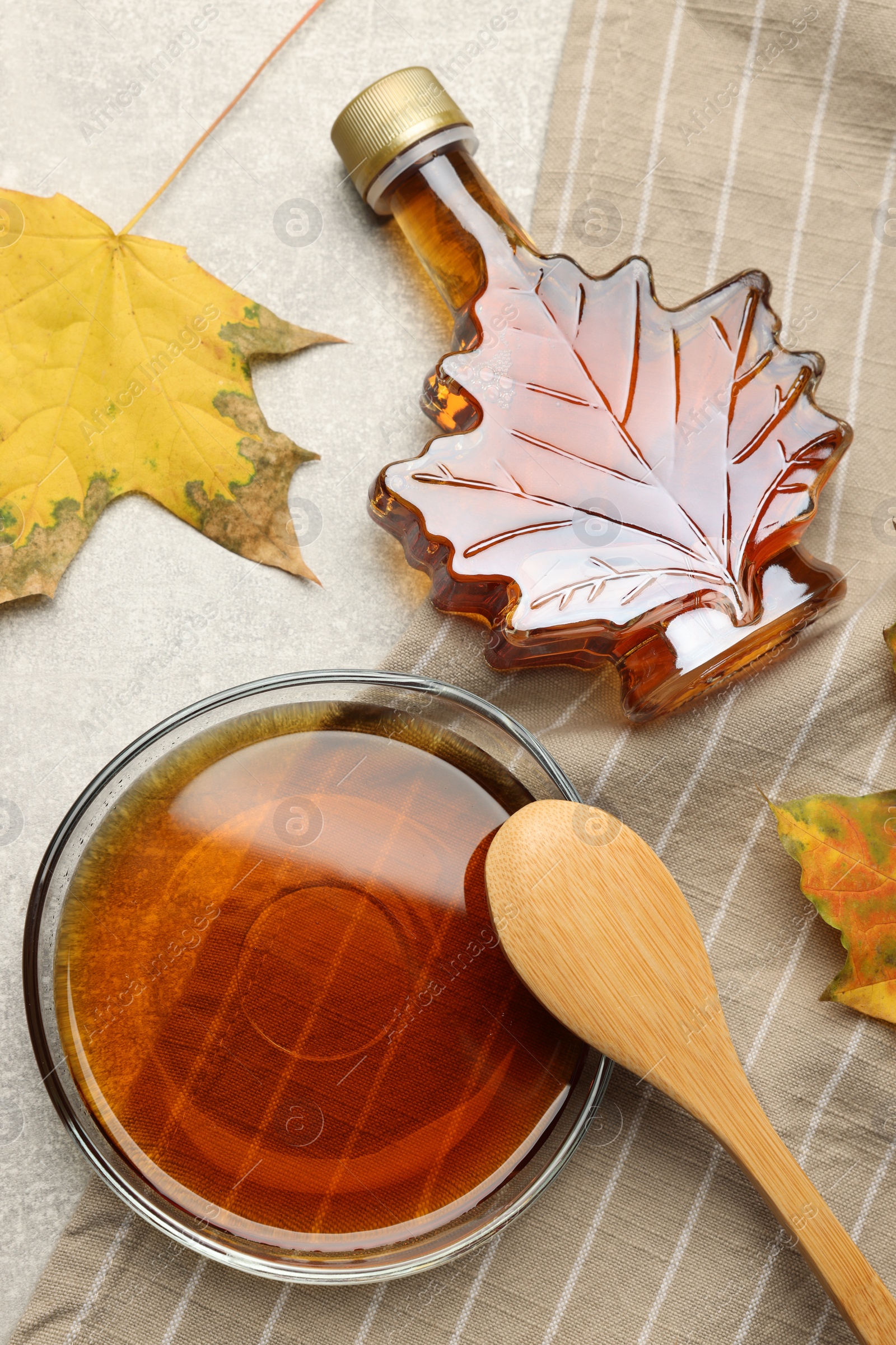 Photo of Flat lay composition with tasty maple syrup and dry leaves on light grey table