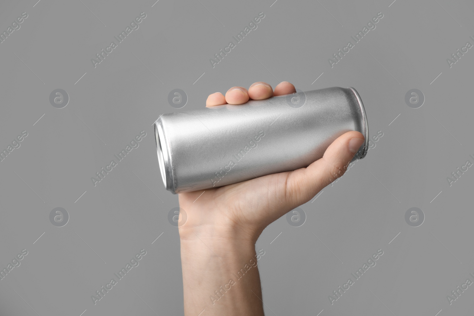 Photo of Man holding aluminum can with beverage on grey background, closeup. Space for design