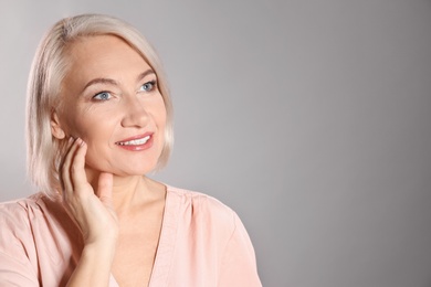 Photo of Portrait of charming mature woman with healthy beautiful face skin and natural makeup on grey background, space for text