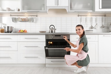 Photo of Young woman baking something in oven at home