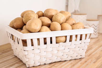 Photo of Basket with potatoes on wooden kitchen counter. Orderly storage