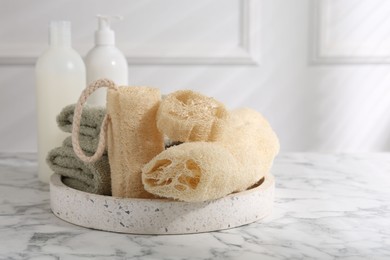 Loofah sponges, towels and cosmetic products on white marble table, space for text