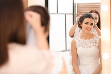 Photo of Professional hairdresser working with young bride in salon