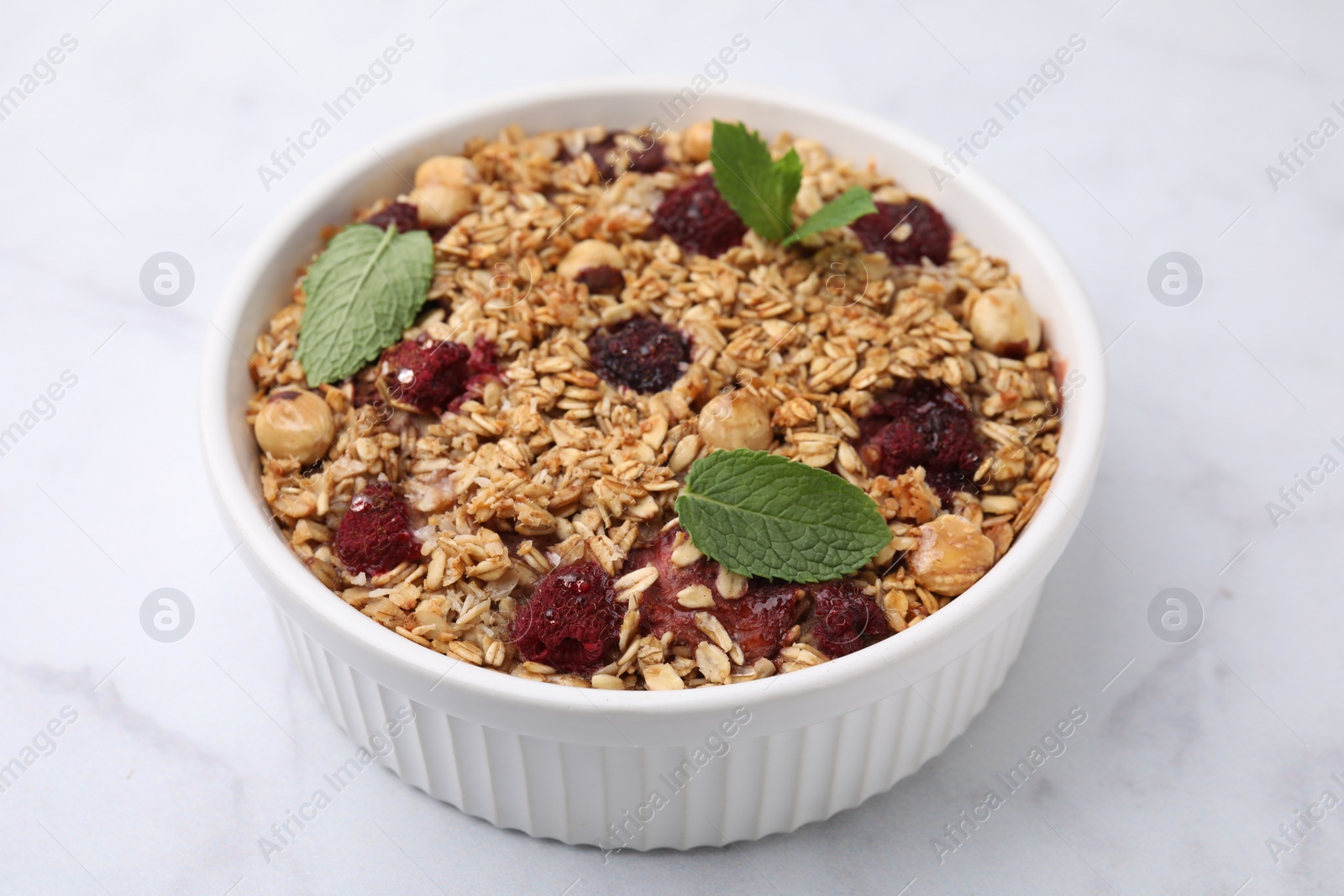 Photo of Tasty baked oatmeal with berries and nuts on white marble table, closeup