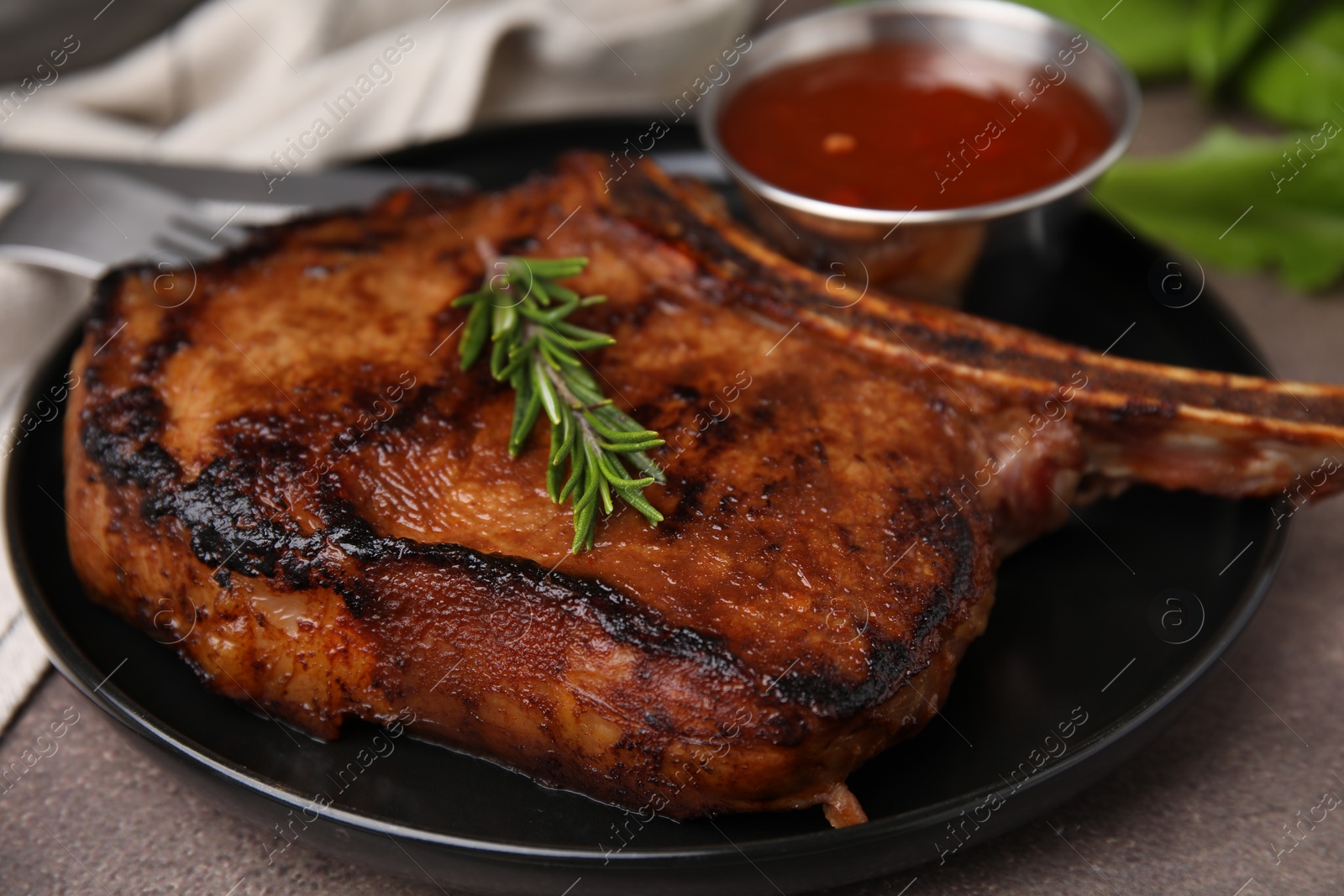Photo of Tasty grilled meat, rosemary and marinade on brown textured table, closeup