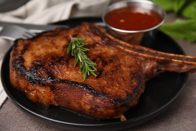 Photo of Tasty grilled meat, rosemary and marinade on brown textured table, closeup