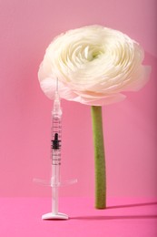 Photo of Cosmetology. Medical syringe and ranunculus flower on pink background