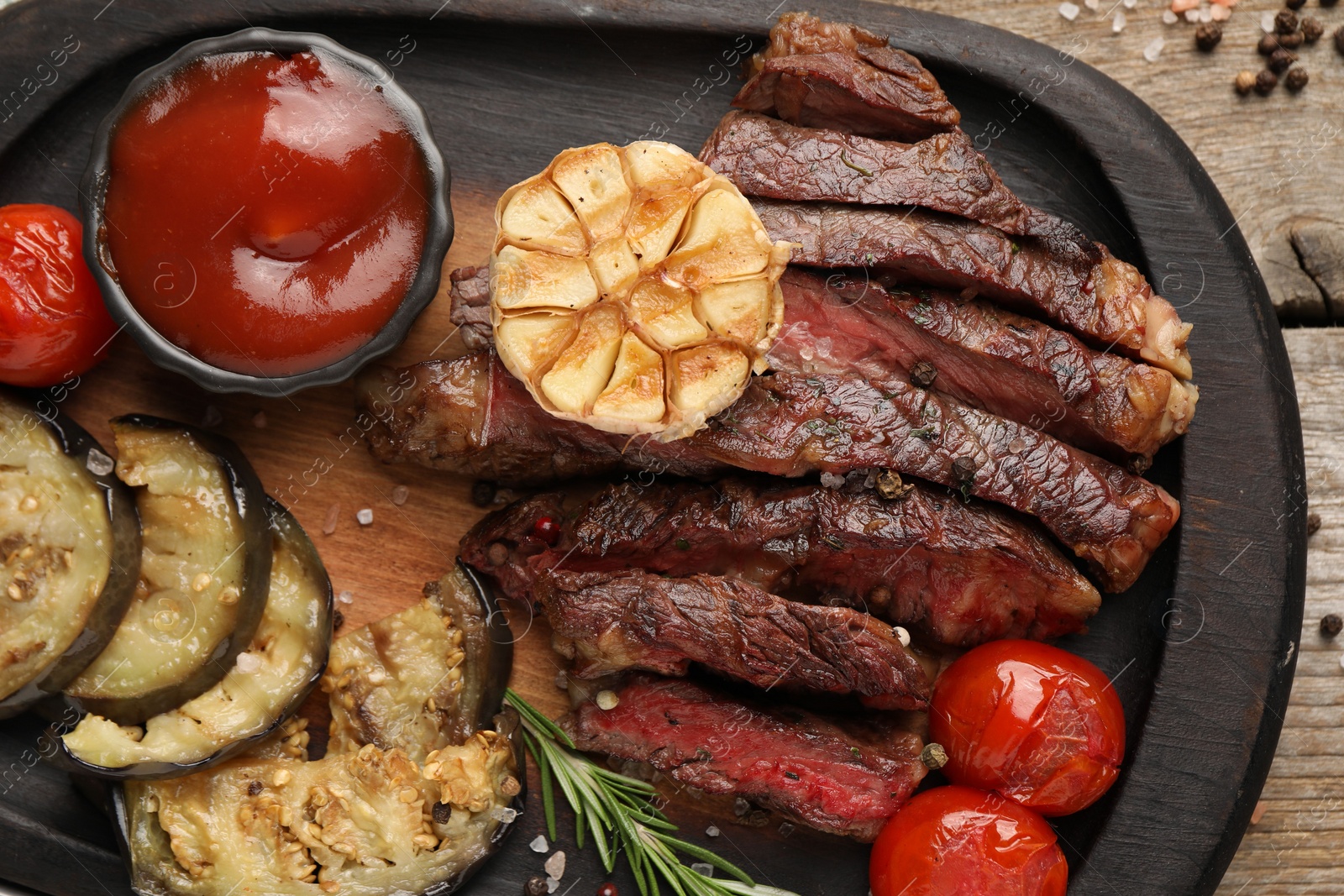 Photo of Delicious grilled beef with vegetables, tomato sauce and spices on table, top view