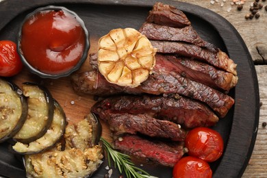 Delicious grilled beef with vegetables, tomato sauce and spices on table, top view