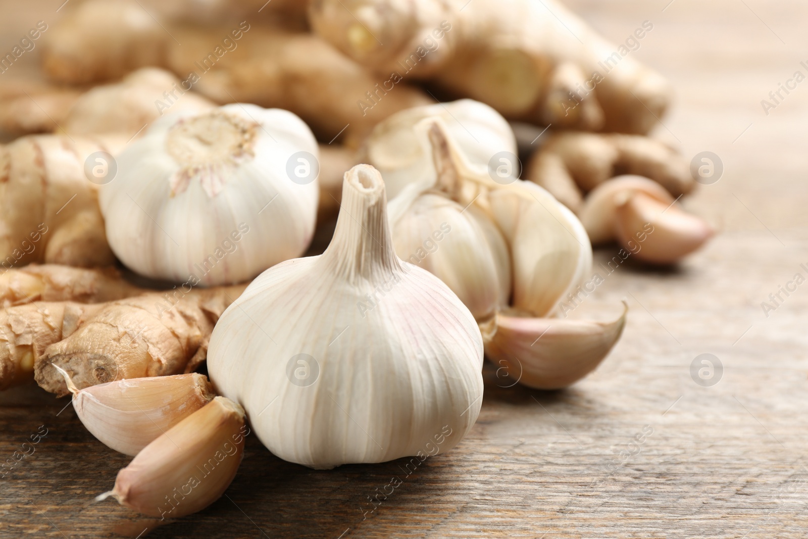 Photo of Ginger and fresh garlic on wooden table, closeup. Natural cold remedies