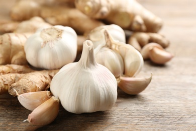 Photo of Ginger and fresh garlic on wooden table, closeup. Natural cold remedies