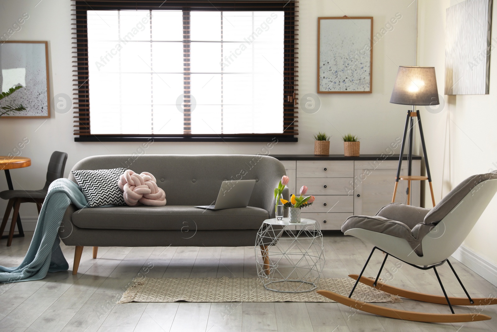 Photo of Interior of cozy living room with grey sofa and rocking chair