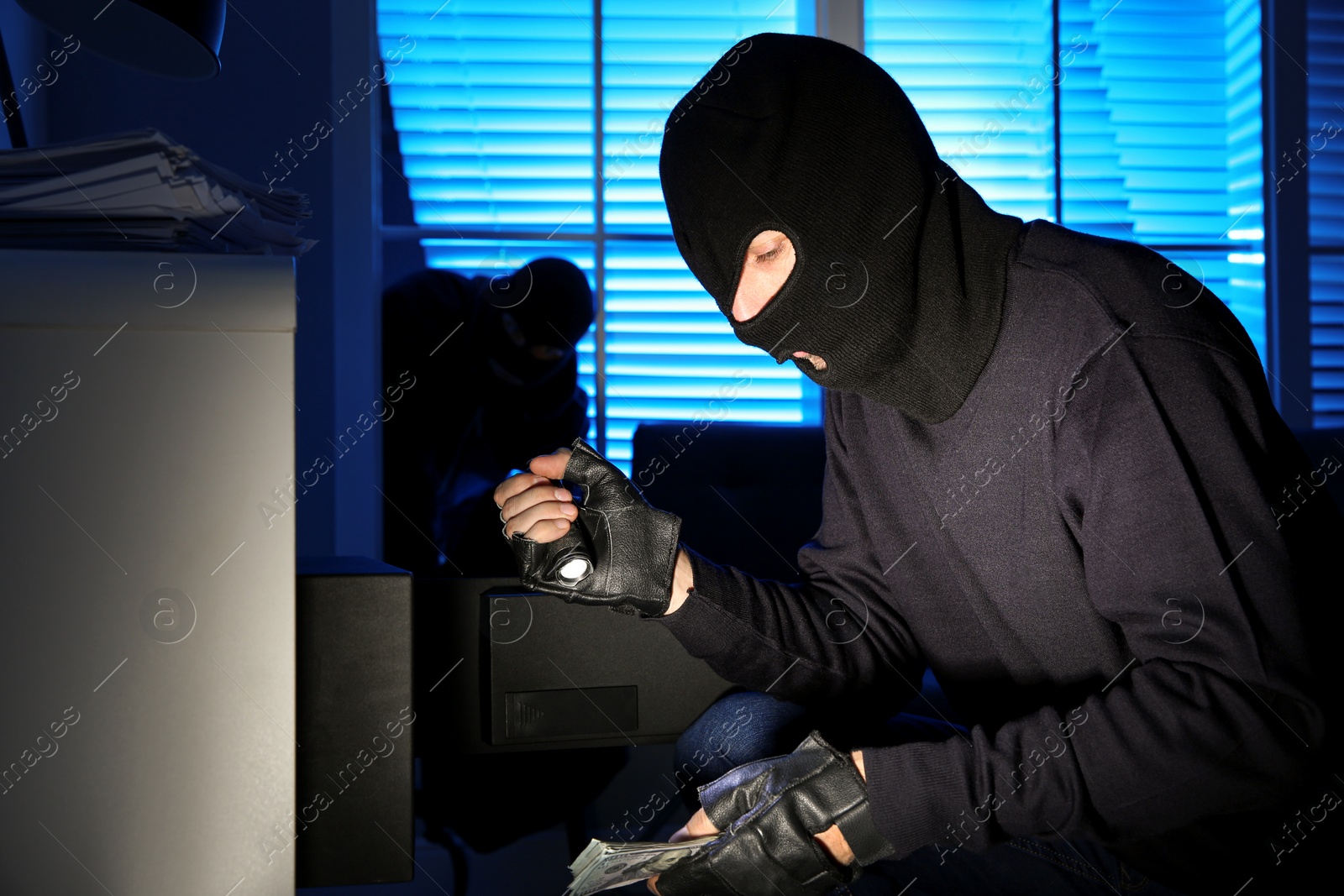 Photo of Thieves taking money out of steel safe indoors at night