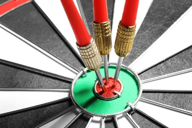 Dart board with red arrows hitting target, closeup