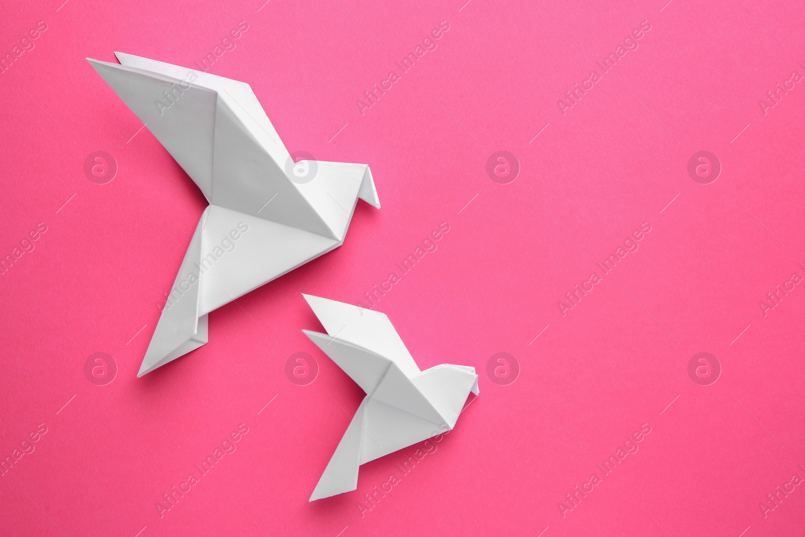 Photo of Beautiful white origami birds on pink background, flat lay. Space for text