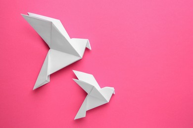 Photo of Beautiful white origami birds on pink background, flat lay. Space for text