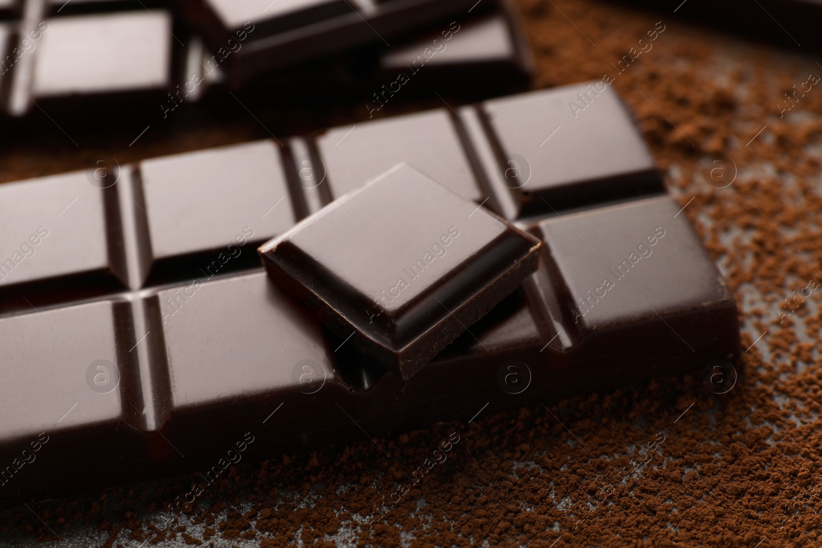 Photo of Delicious dark chocolate and cocoa powder on table, closeup