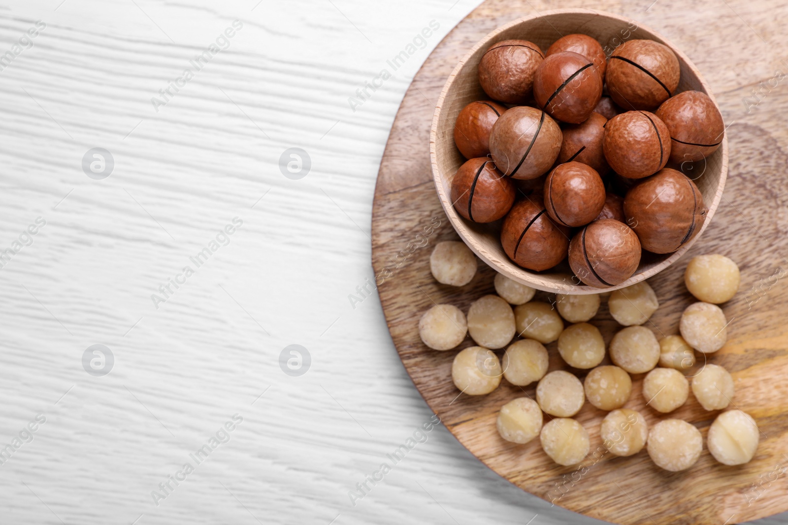 Photo of Delicious Macadamia nuts on white wooden table, top view. Space for text