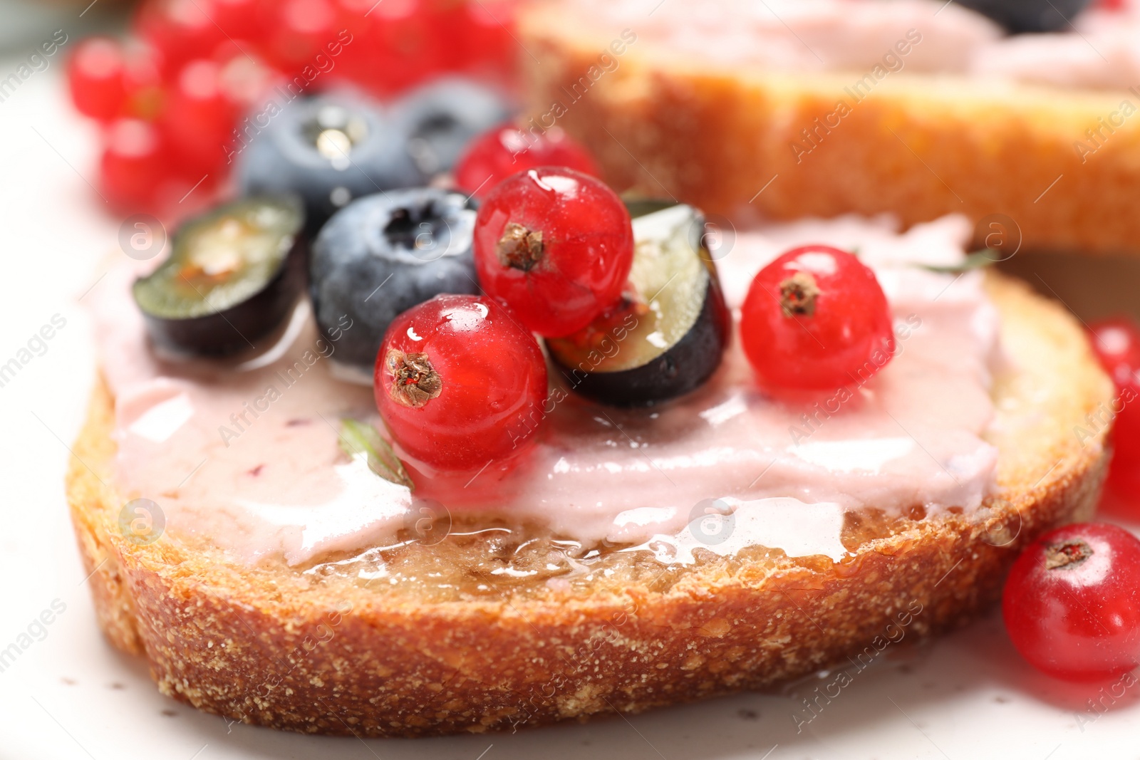 Photo of Tasty sandwiches with cream cheese, blueberries and red currants, closeup
