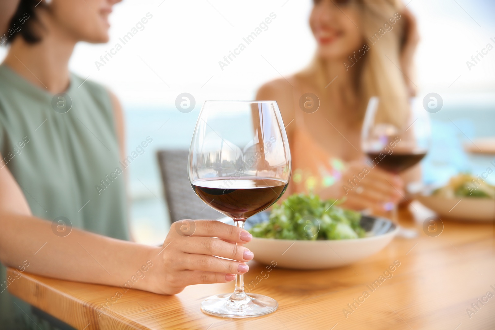 Photo of Young women with glasses of wine at table