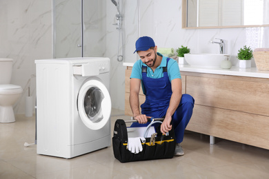 Repairman with toolbox near washing machine in bathroom