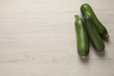 Photo of Raw ripe zucchinis on white wooden table, flat lay. Space for text