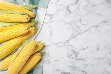 Bunch of corn cobs on white marble table, flat lay. Space for text