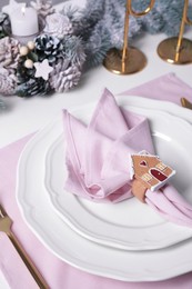 Photo of Plates and pink fabric napkin with beautiful decorative ring on white table
