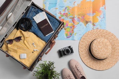 Photo of Flat lay composition with packed suitcase and travel accessories on grey background. Summer vacation