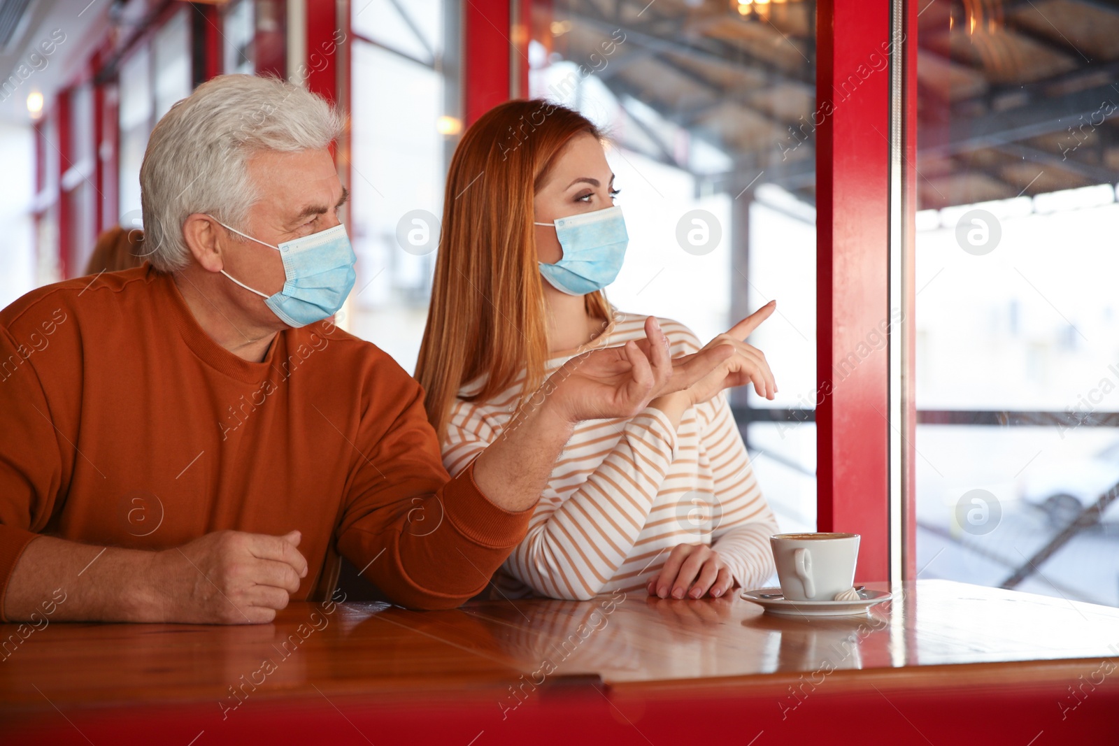 Photo of People with medical masks in cafe. Virus protection