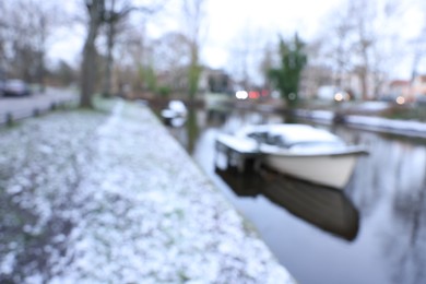 Blurred view of water canal and moored boat covered with snow on winter day