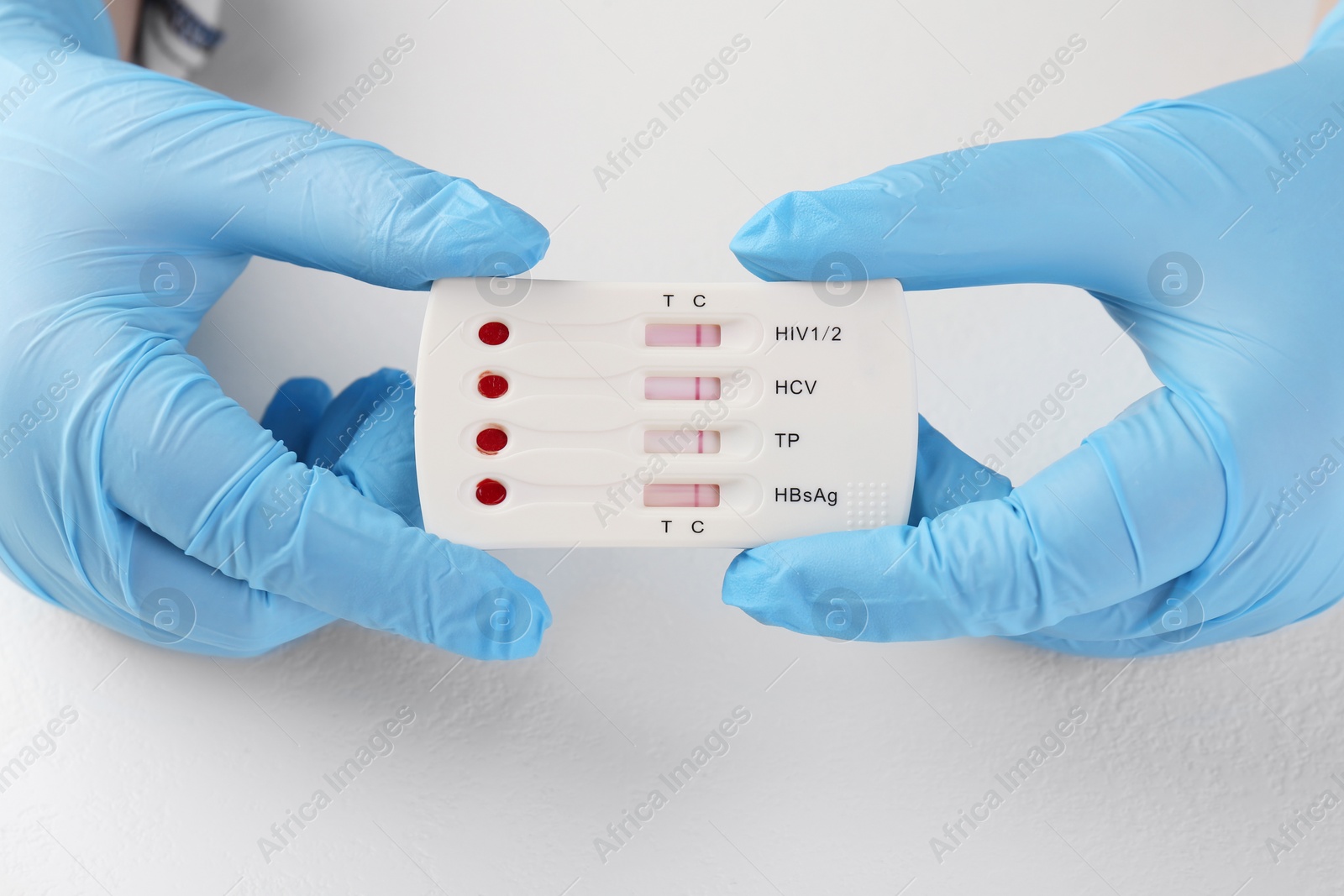 Photo of Doctor holding disposable multi-infection express test at white table, closeup