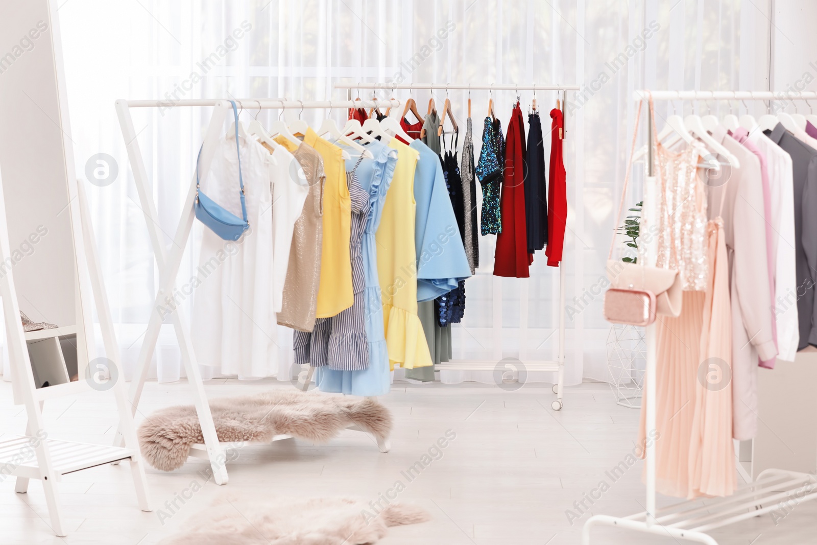 Photo of Racks with stylish clothes in light room