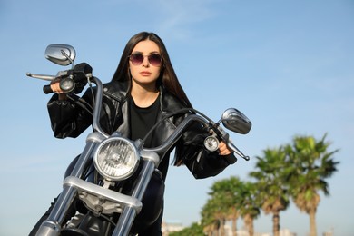 Beautiful young woman riding motorcycle on sunny day