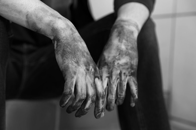 Photo of Dirty worker sitting on stairs, closeup of hands. Black and white effect