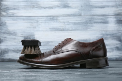 Photo of Men's leather shoes and cleaning brush on grey table