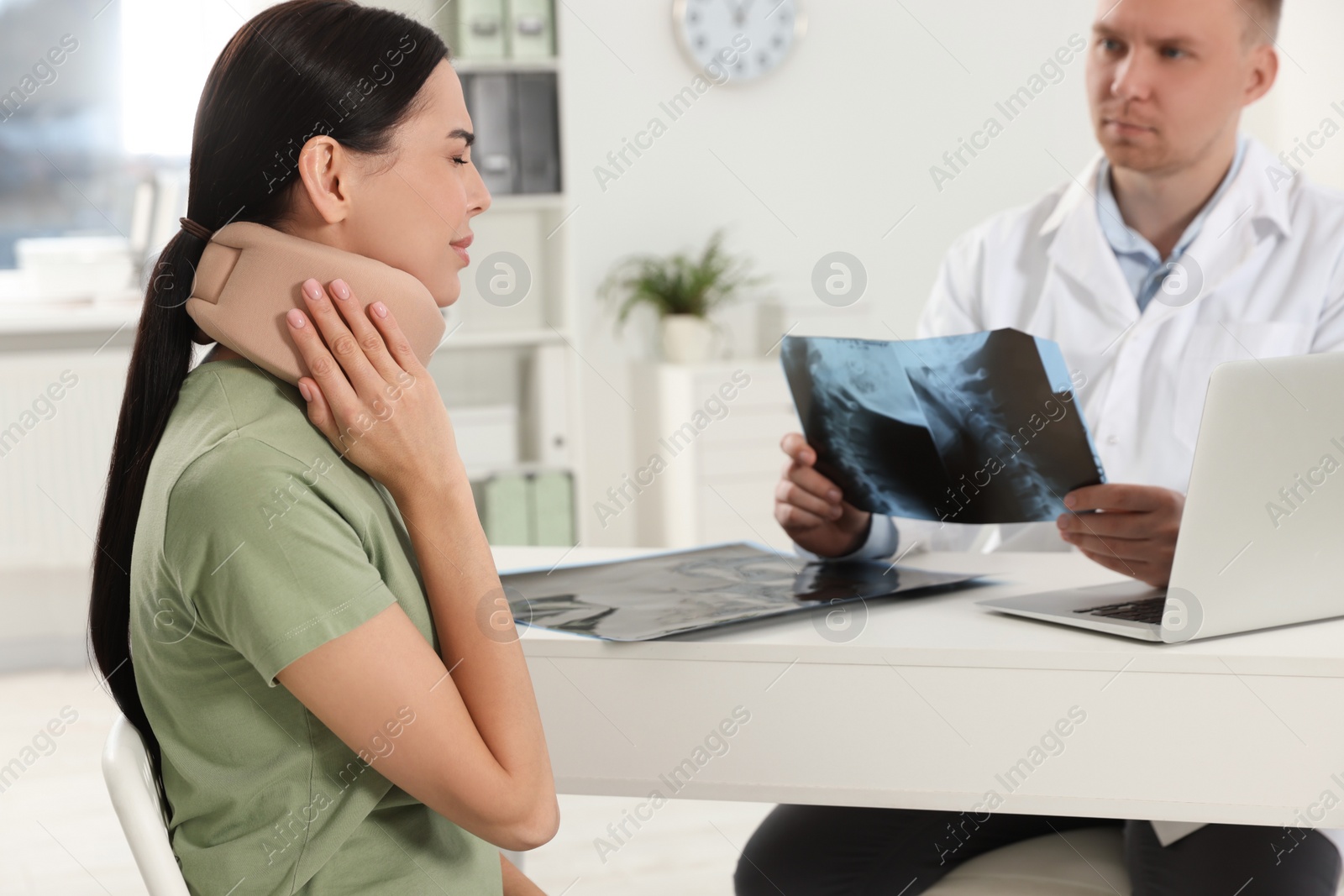 Photo of Doctor with neck MRI image consulting patient in clinic