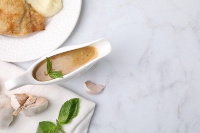 Photo of Delicious turkey gravy, basil and garlic on white marble table, flat lay. Space for text