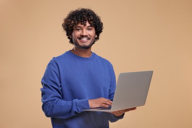 Photo of Smiling man with laptop on beige background. Space for text