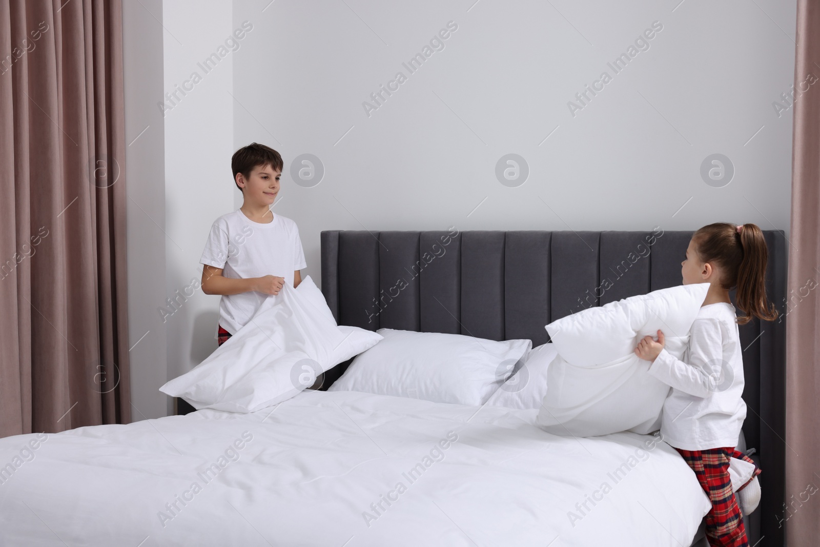 Photo of Brother and sister changing bed linens together in bedroom