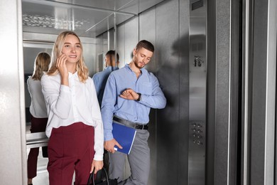 Young coworkers taking ride in elevator together