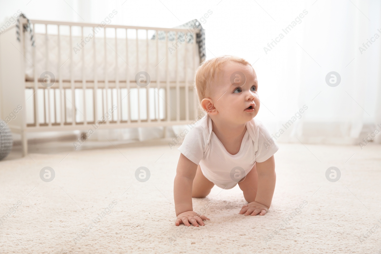 Photo of Cute little baby crawling on carpet indoors